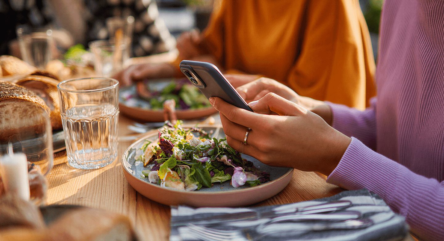 Woman using smartphone outdoor restaurant dining